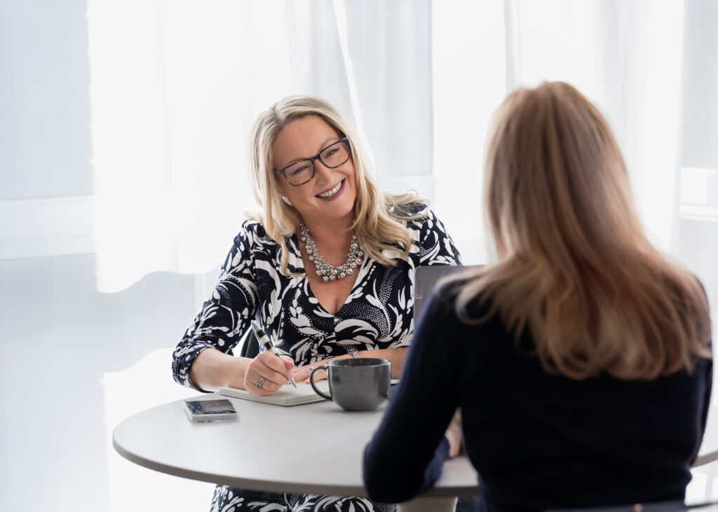 Clare Bailey sitting at a table talking with another woman