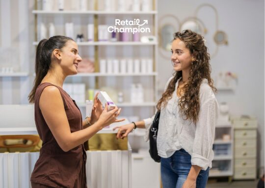 Two women in a shop talking, one holding a small bo