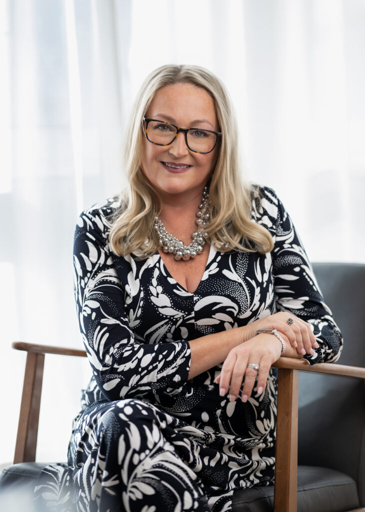 Clare Bailey in black and white dress, sitting in a chair