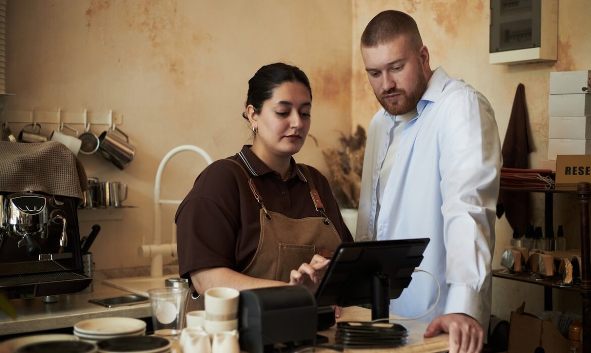 An employee helping a colleague learn to use a retail business system.